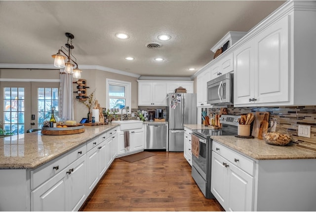 kitchen with visible vents, crown molding, a peninsula, stainless steel appliances, and a sink