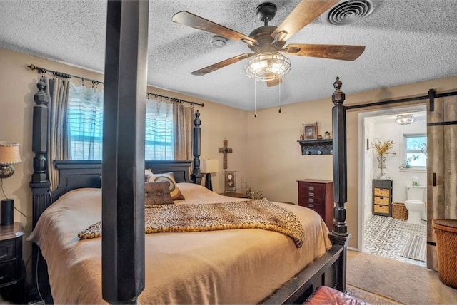 bedroom with a barn door, visible vents, carpet floors, and a textured ceiling