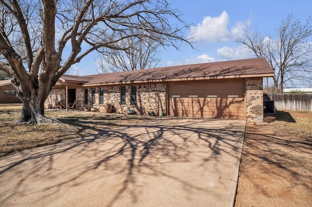 view of front of house featuring brick siding, an attached garage, concrete driveway, and fence