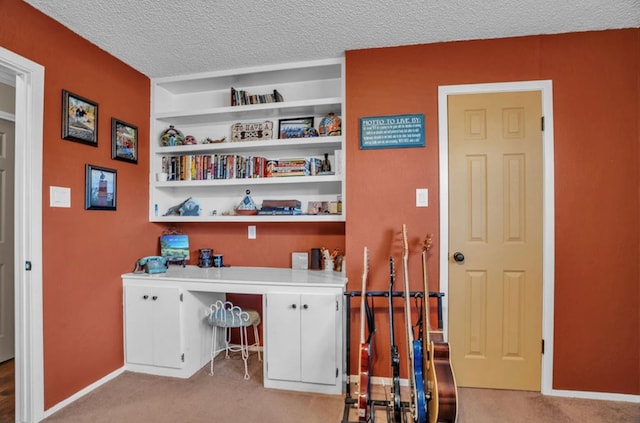 home office featuring light colored carpet, built in shelves, a textured ceiling, and baseboards