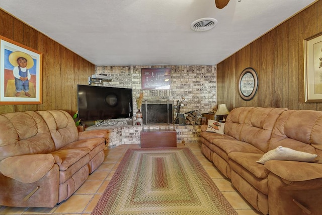 living room featuring wooden walls, a fireplace, light tile patterned floors, and ceiling fan