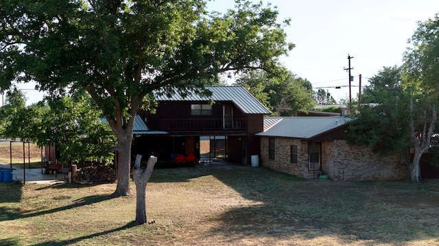 rear view of house with a lawn and a balcony