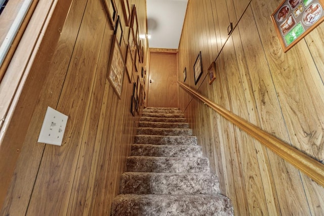 stairway with wooden walls and hardwood / wood-style flooring