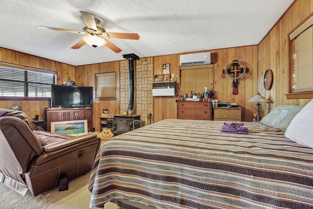 bedroom featuring a wood stove, ceiling fan, a textured ceiling, a wall mounted AC, and carpet floors