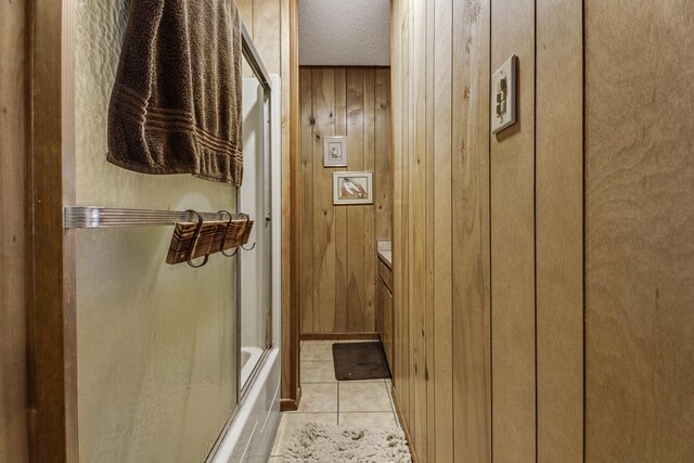 bathroom featuring tile patterned floors, wood walls, vanity, and a textured ceiling