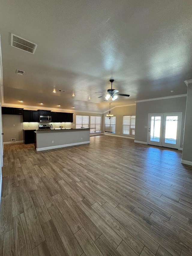 unfurnished living room with dark wood-style floors, ceiling fan, visible vents, and crown molding