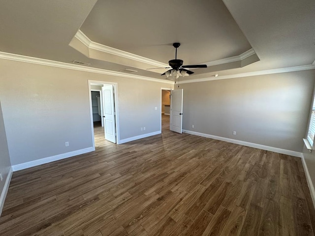 unfurnished bedroom with ornamental molding, a raised ceiling, dark wood finished floors, and baseboards