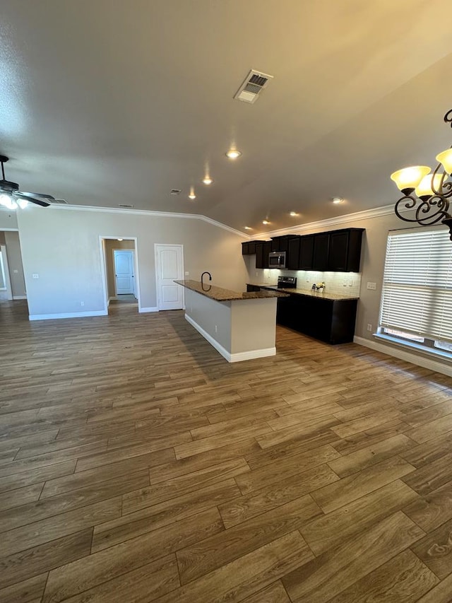 kitchen featuring crown molding, stainless steel microwave, visible vents, open floor plan, and dark cabinetry