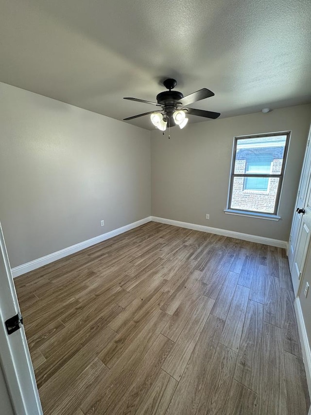 spare room featuring ceiling fan, a textured ceiling, baseboards, and wood finished floors