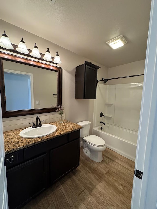 bathroom featuring toilet, wood finished floors, tub / shower combination, vanity, and backsplash