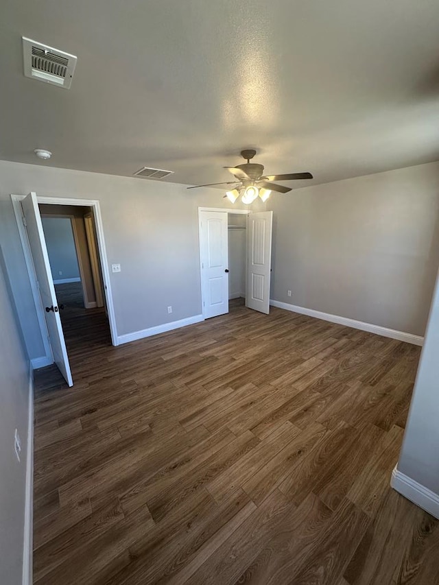 unfurnished bedroom with dark wood-type flooring, a closet, visible vents, and baseboards