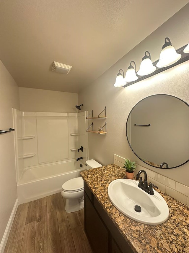 bathroom with bathtub / shower combination, toilet, wood finished floors, visible vents, and vanity