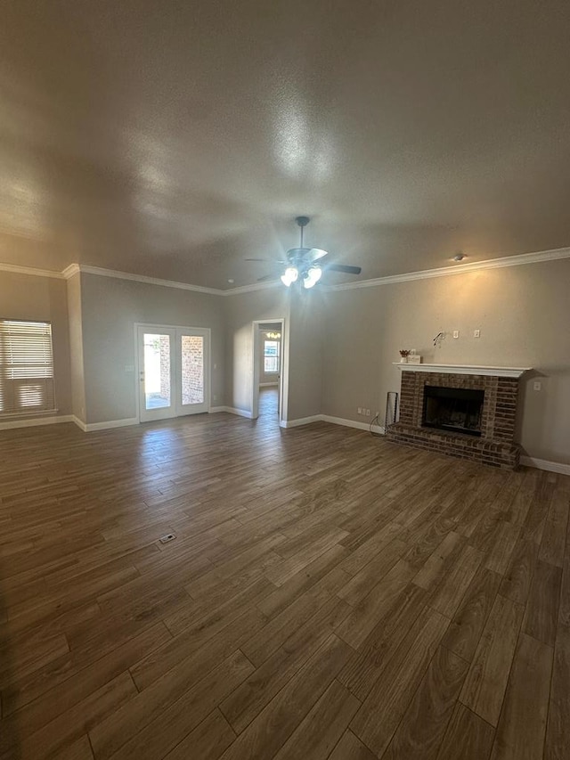 unfurnished living room with ornamental molding, a brick fireplace, dark wood finished floors, and baseboards