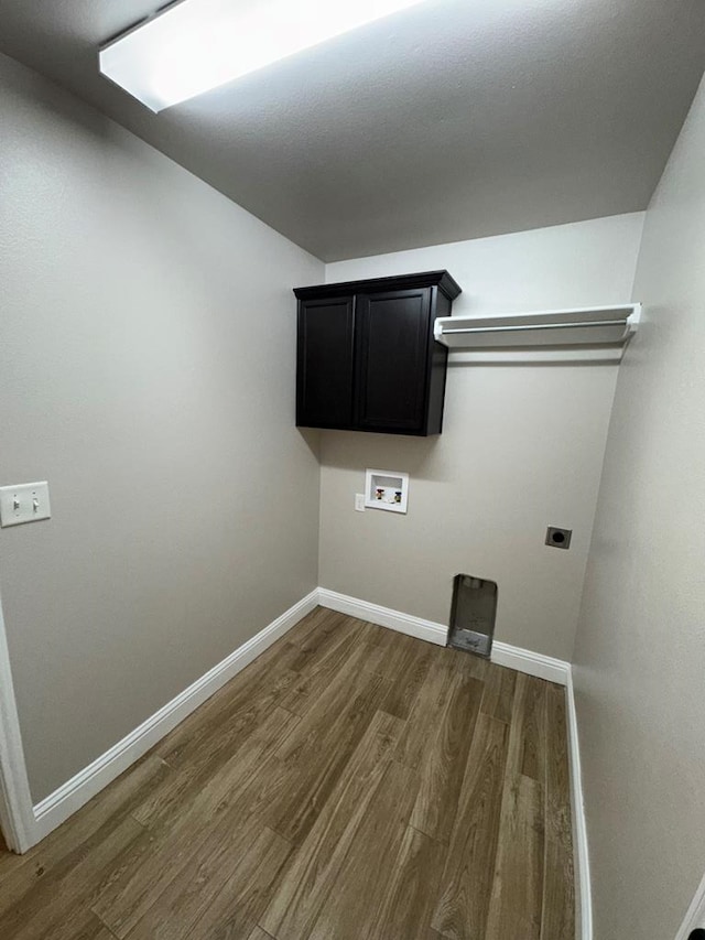 washroom featuring hookup for an electric dryer, washer hookup, wood finished floors, baseboards, and cabinet space