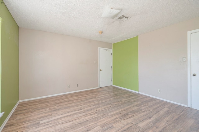 unfurnished room with hardwood / wood-style floors and a textured ceiling