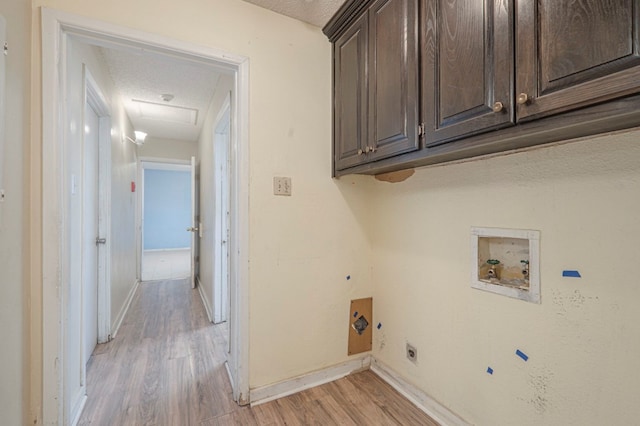 clothes washing area featuring cabinets, a textured ceiling, light wood-type flooring, hookup for a washing machine, and electric dryer hookup