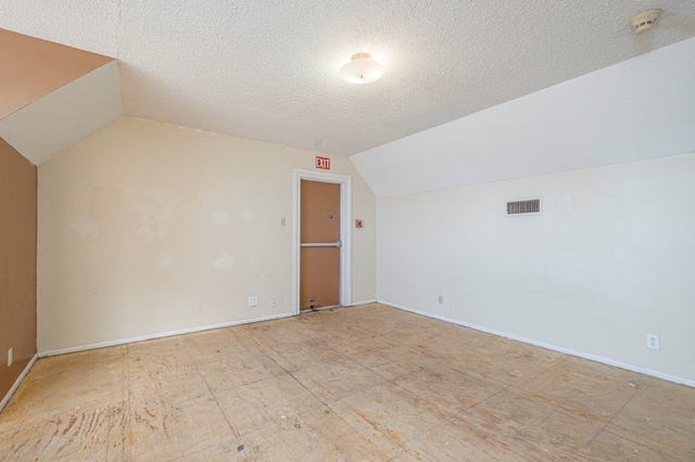 additional living space featuring vaulted ceiling and a textured ceiling