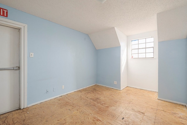 additional living space with lofted ceiling and a textured ceiling