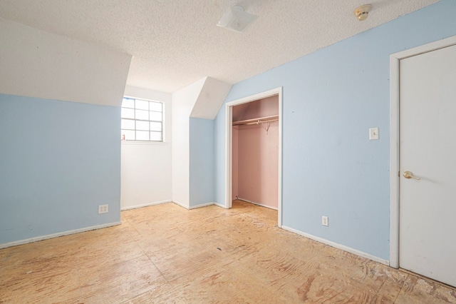 unfurnished bedroom with vaulted ceiling, a closet, and a textured ceiling