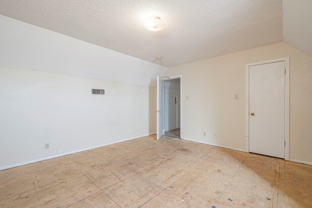 additional living space with lofted ceiling and a textured ceiling