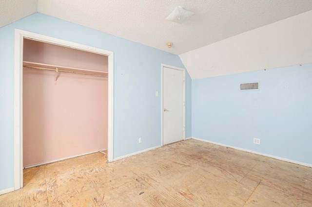 unfurnished bedroom featuring a closet, lofted ceiling, and a textured ceiling