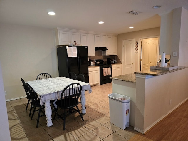 3102 Travis Ave, Midland, TX 79701 - kitchen featuring black appliances, under cabinet range hood, white cabinets, a peninsula, and dark stone countertops