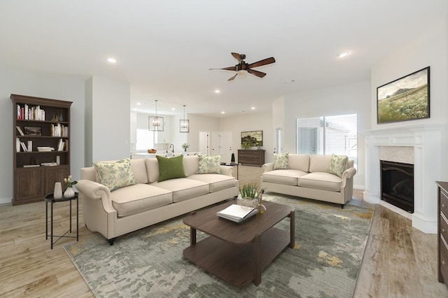 living room featuring recessed lighting, light wood-style floors, ceiling fan, and a fireplace