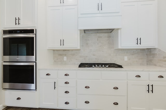 kitchen featuring white cabinetry, decorative backsplash, light stone countertops, and stainless steel appliances