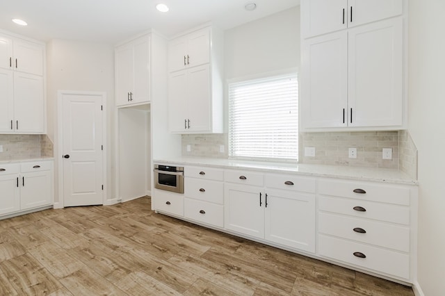 kitchen featuring stainless steel oven, white cabinetry, and light wood finished floors