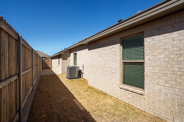 view of home's exterior featuring cooling unit, brick siding, and a fenced backyard