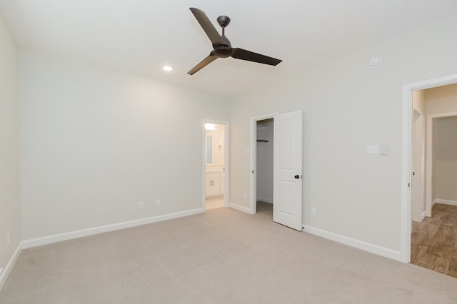 unfurnished bedroom with a spacious closet, connected bathroom, light carpet, and baseboards