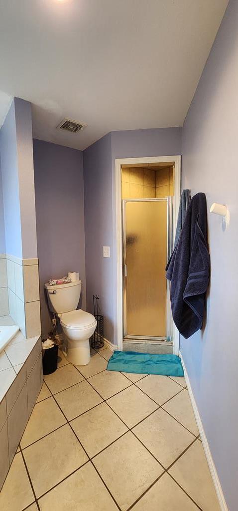 bathroom featuring a stall shower, visible vents, toilet, and tile patterned floors