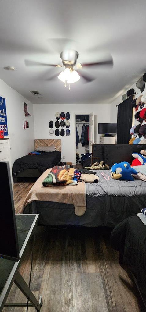 bedroom with ceiling fan, visible vents, and wood finished floors