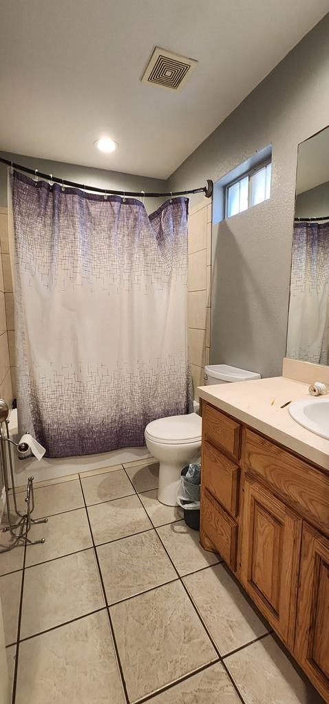 bathroom with visible vents, toilet, curtained shower, tile patterned flooring, and vanity