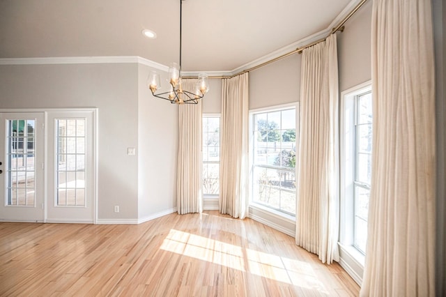 spare room featuring hardwood / wood-style floors, crown molding, and a chandelier