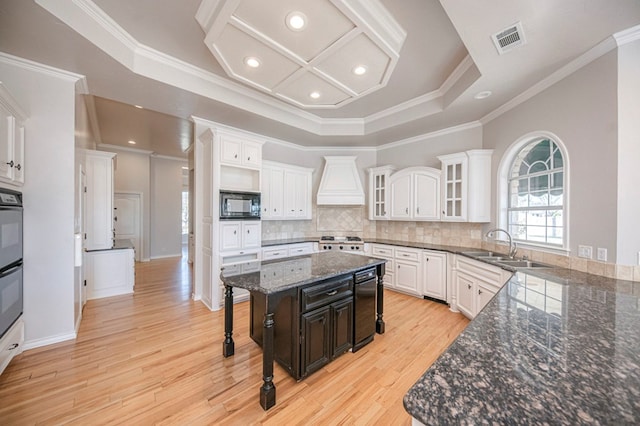 kitchen with crown molding, black appliances, white cabinetry, light hardwood / wood-style floors, and a kitchen island