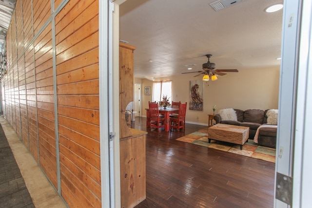 corridor with dark hardwood / wood-style floors and wooden walls