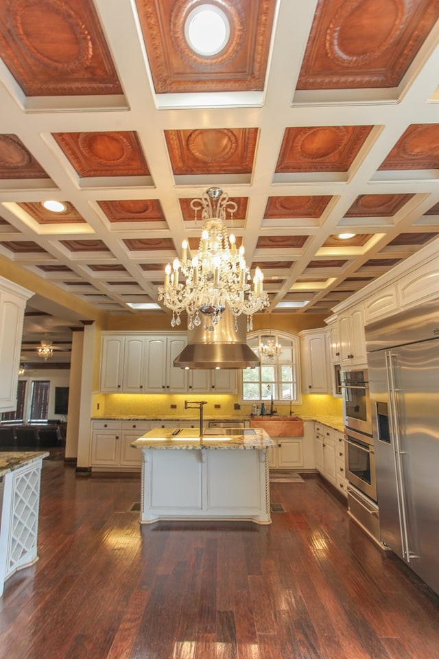 kitchen with appliances with stainless steel finishes, pendant lighting, dark wood-type flooring, and coffered ceiling