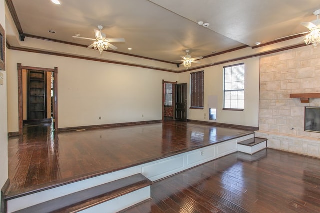 unfurnished room with crown molding, ceiling fan, dark hardwood / wood-style flooring, and a fireplace