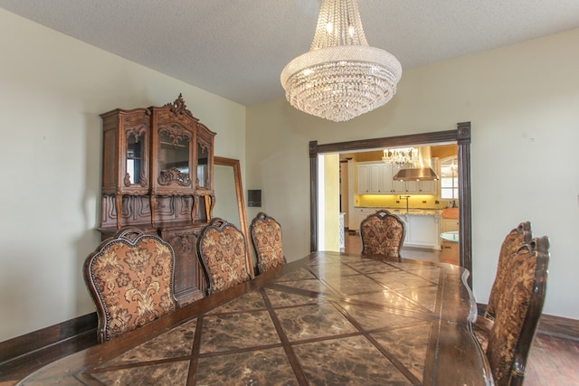 dining area with dark tile patterned floors, a textured ceiling, and a chandelier