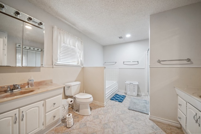 bathroom featuring visible vents, toilet, a garden tub, a textured ceiling, and vanity