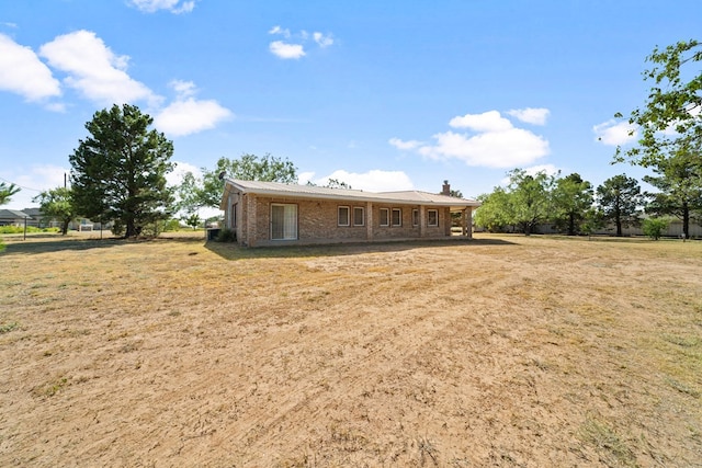 back of property with a yard, brick siding, and a chimney