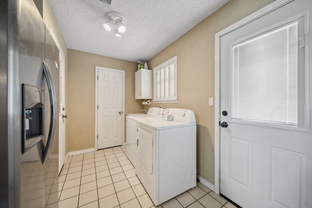 laundry area featuring light tile patterned floors, a textured ceiling, water heater, cabinet space, and washing machine and clothes dryer