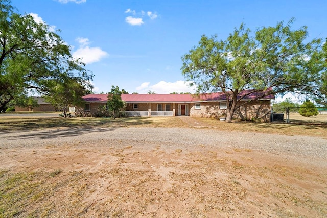 single story home with dirt driveway and fence