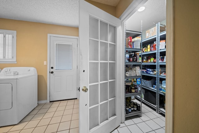 washroom featuring washer / clothes dryer, light tile patterned flooring, a textured ceiling, and laundry area