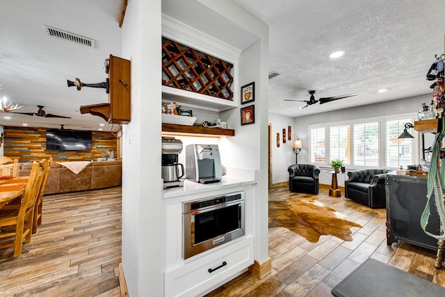 kitchen featuring ceiling fan, stainless steel oven, white cabinets, and a textured ceiling