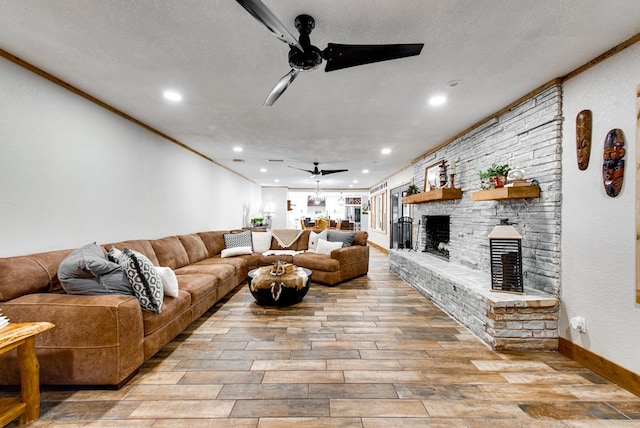 living room with crown molding, ceiling fan, a fireplace, and a textured ceiling