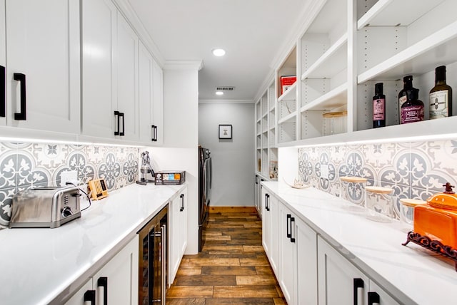 kitchen with dark hardwood / wood-style floors, tasteful backsplash, white cabinets, ornamental molding, and light stone countertops