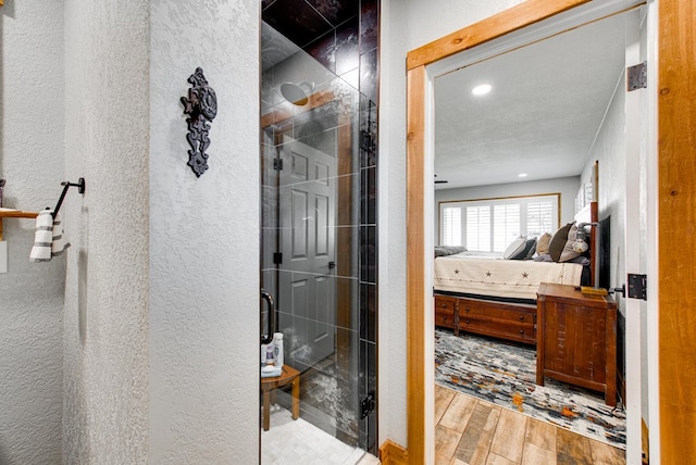 bathroom featuring a textured ceiling and a shower with shower door