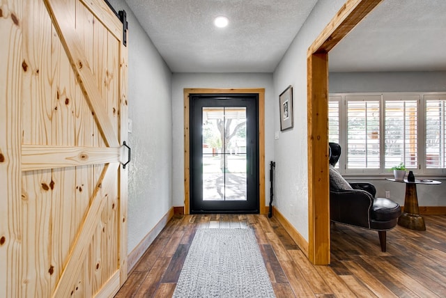 entryway with a barn door, hardwood / wood-style floors, and a textured ceiling